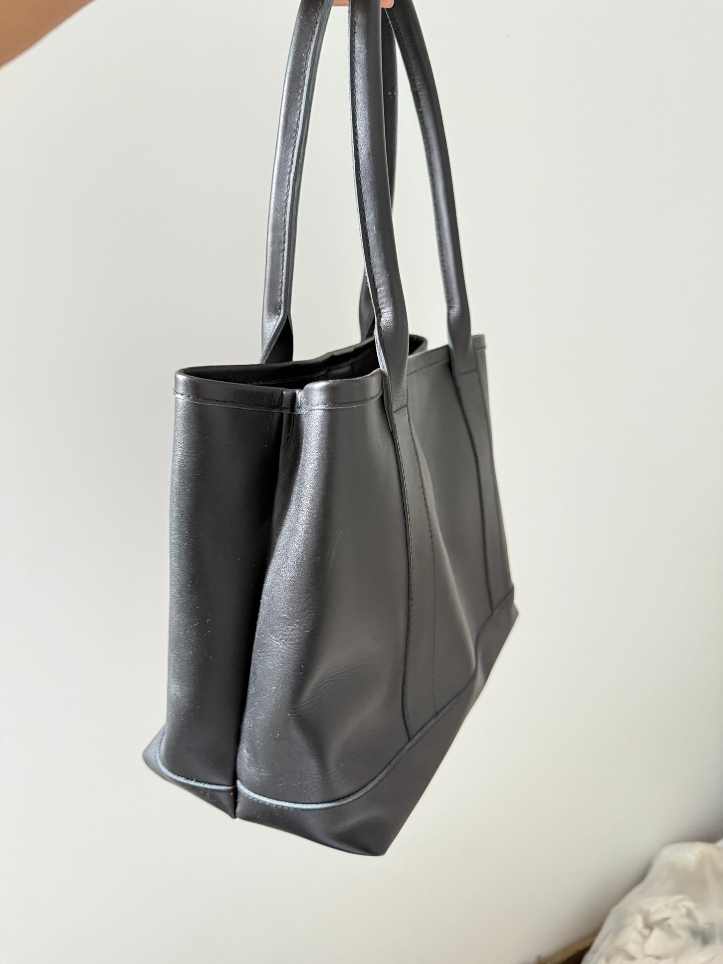 Handmade black leather tote bag with high-quality genuine leather, interior zippered pockets, and adjustable shoulder straps. Spacious enough for a 13-inch laptop, perfect for work or daily use.