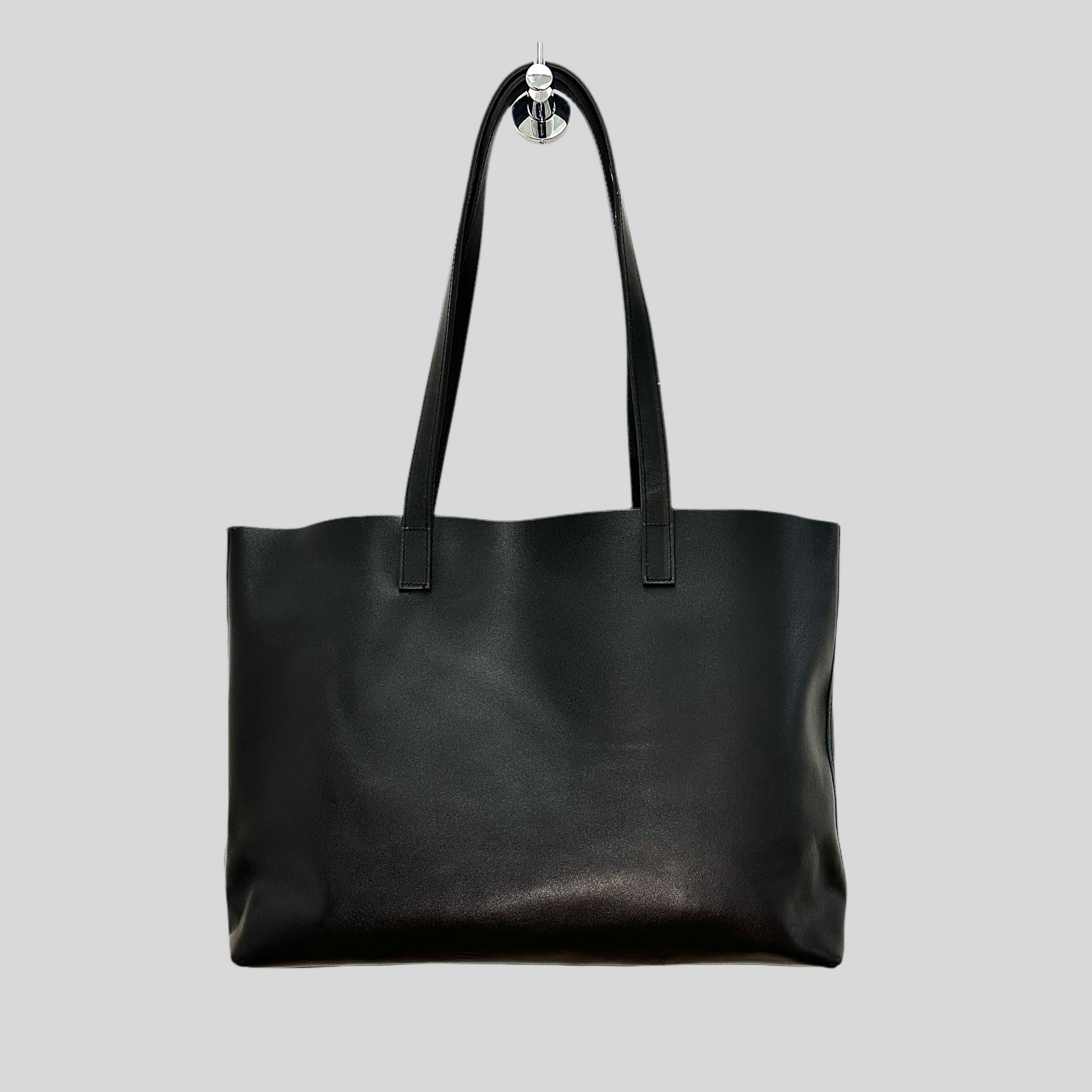 Handmade black leather tote bag styled over a shoulder with casual outfit, highlighting everyday use.