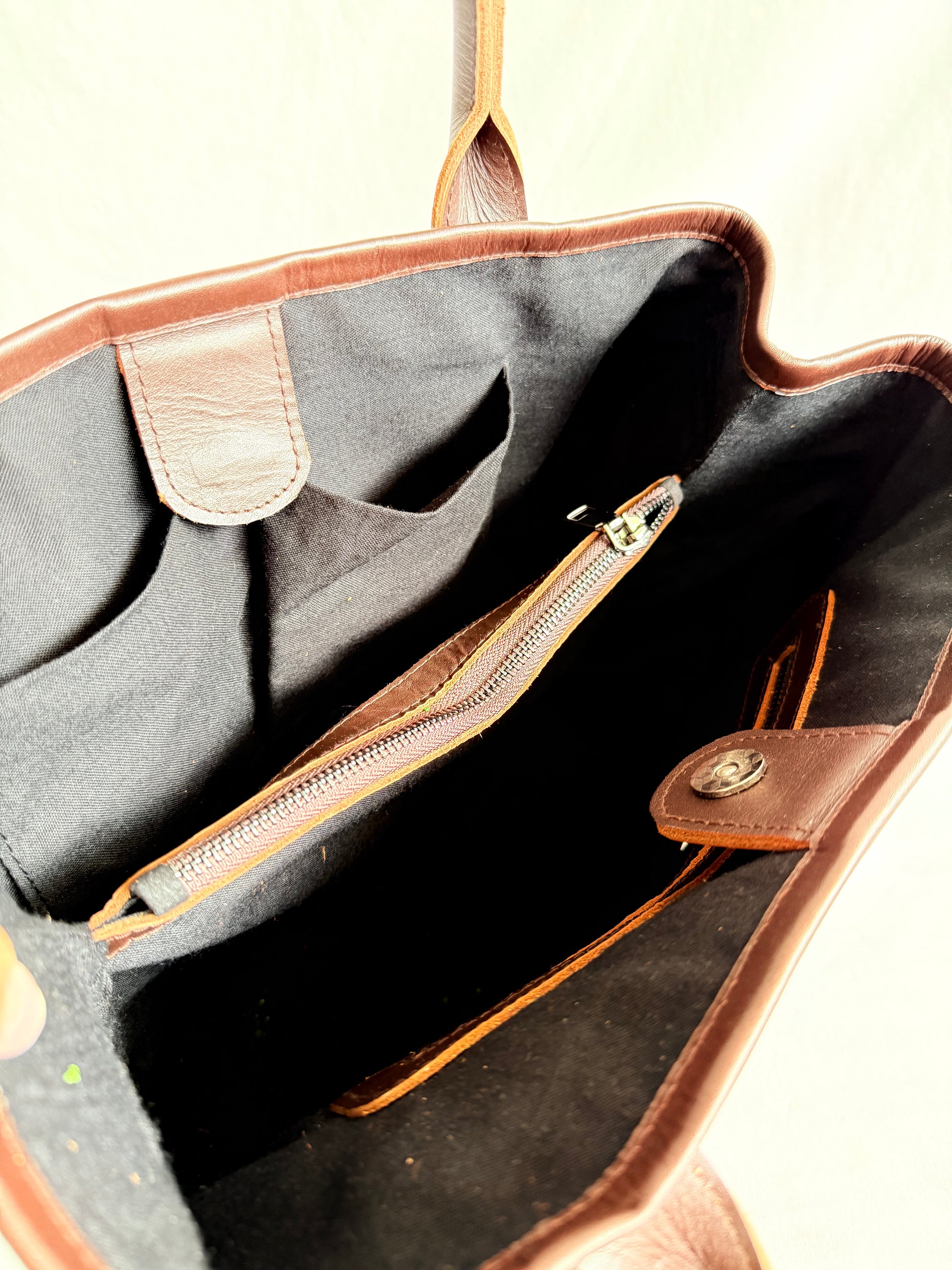 Inside view of handmade leather tote bag with high-quality genuine leather, interior zippered pockets, and adjustable shoulder straps. Spacious enough for a 13-inch laptop, perfect for work or daily use.