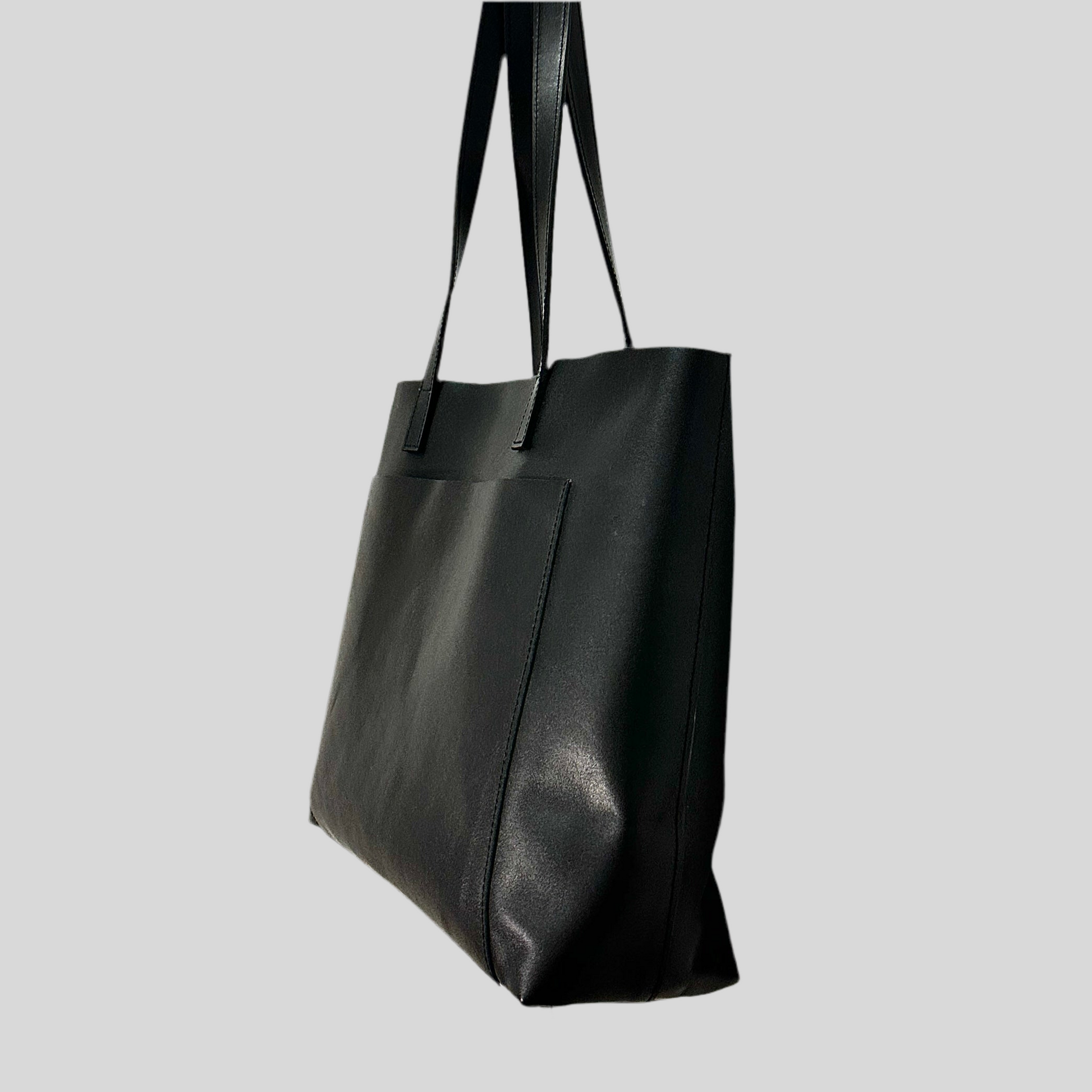 Side view of black shiny Anna tote standing upright, structured and spacious with elegant proportions.