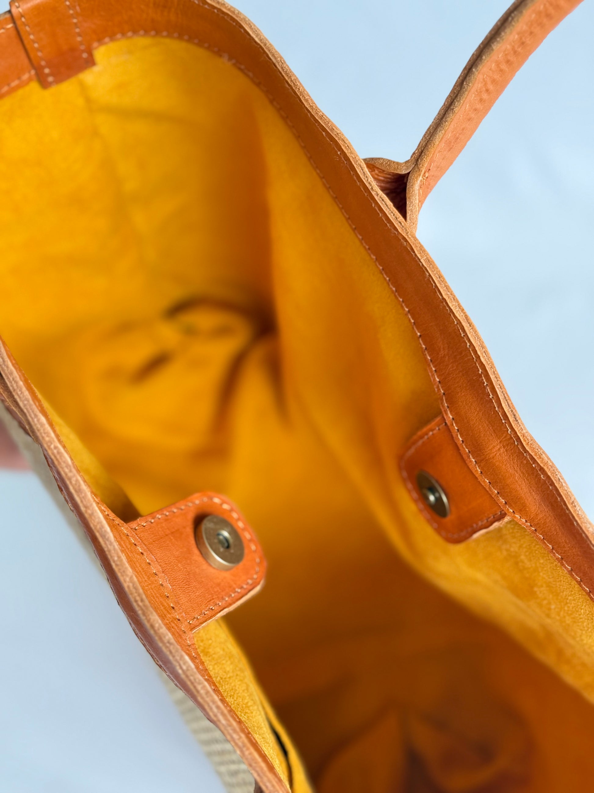 Top-down view of open rattan and leather tote showing spacious interior and magnetic clasp.
